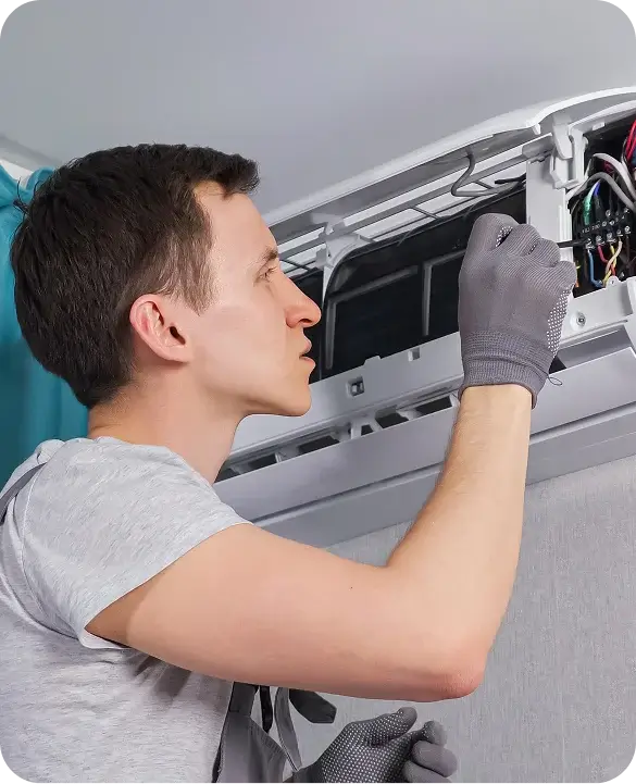 A skilled HVAC technician in gloves performing advanced diagnostics on a wall-mounted air conditioning unit's internal components.