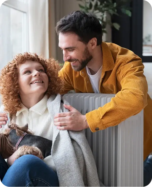 Father and Daughter Smiling by Home Heating Radiator Staying Warm