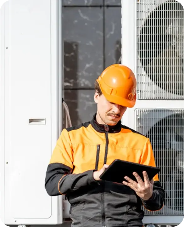 HVAC technician in orange hard hat reviewing tablet next to commercial air conditioning units for Gulf Coast Heating and AC services