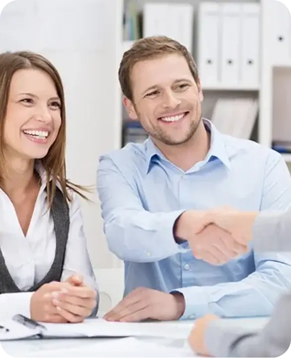 Smiling couple shaking hands with advisor in office