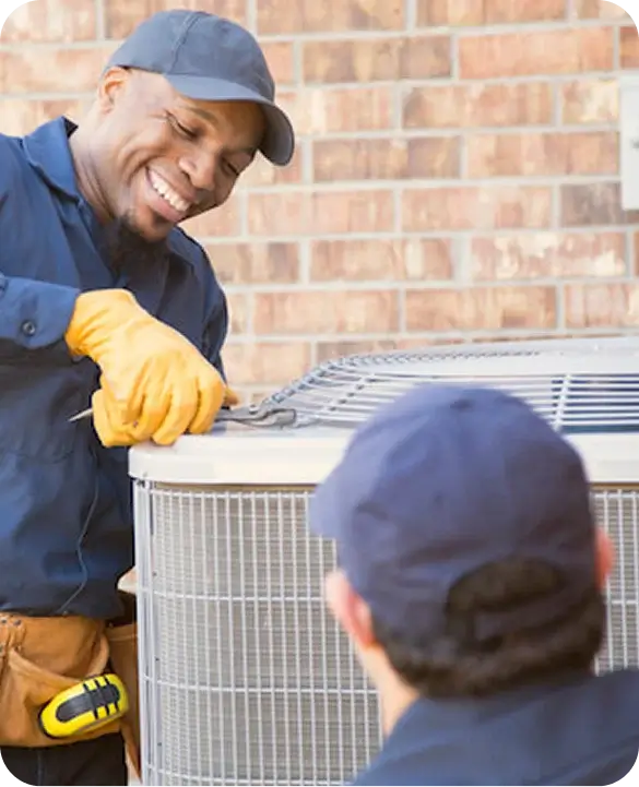 Two Gulf Coast Heating and AC technicians in navy uniforms performing residential AC maintenance on an outdoor condenser unit