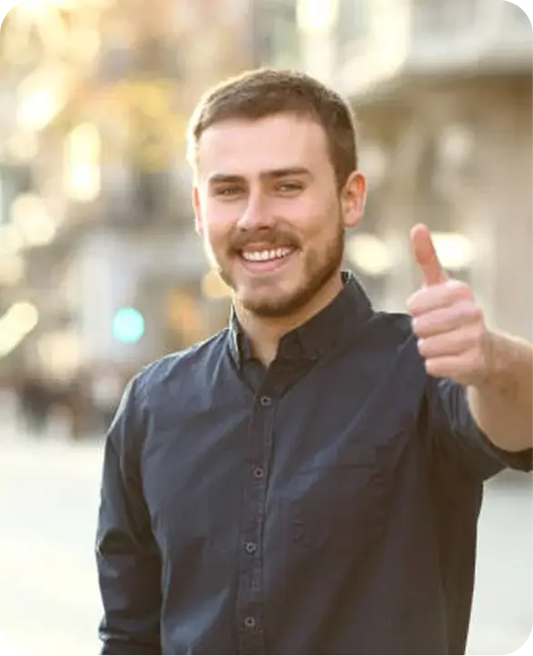 Smiling man giving thumbs up outdoors on street