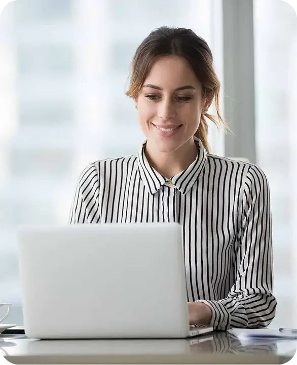 Smiling businesswoman typing on laptop in bright office
