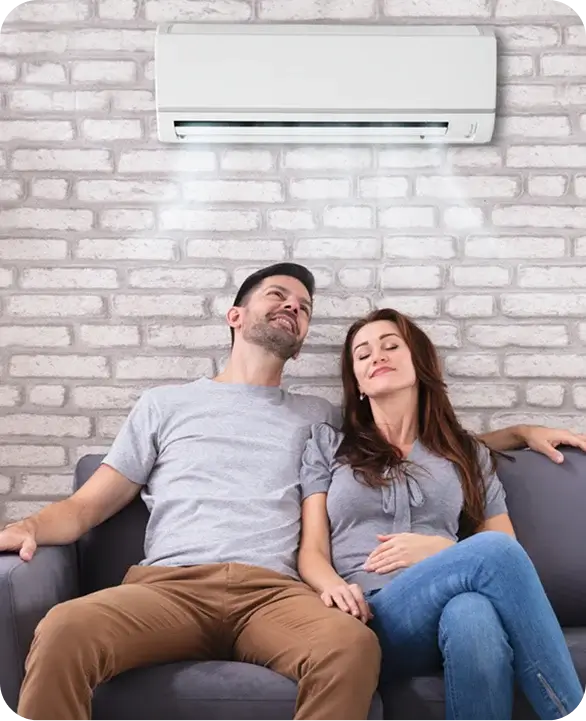 Couple relaxing under cool wall-mounted AC unit at home